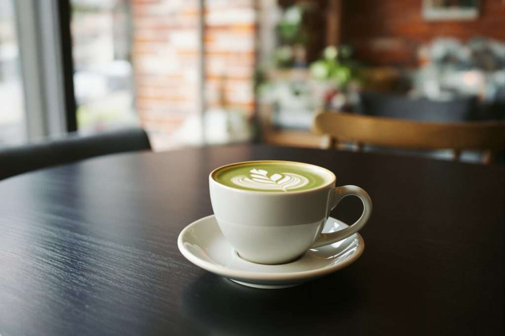 Matcha latte avec latte art sur une table de café à Montréal, mur de brique en arrière-plan